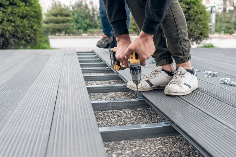 Two carpenters installing composite decking onto a steel frame